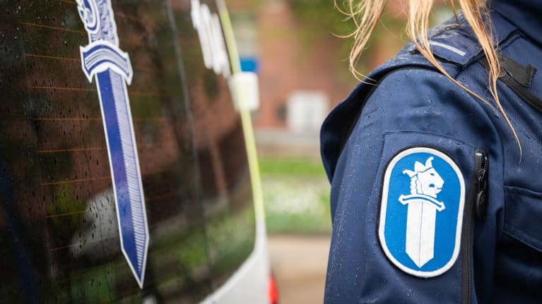 Hihamerkki auton vierelläseisovan poliisin haalarissa.