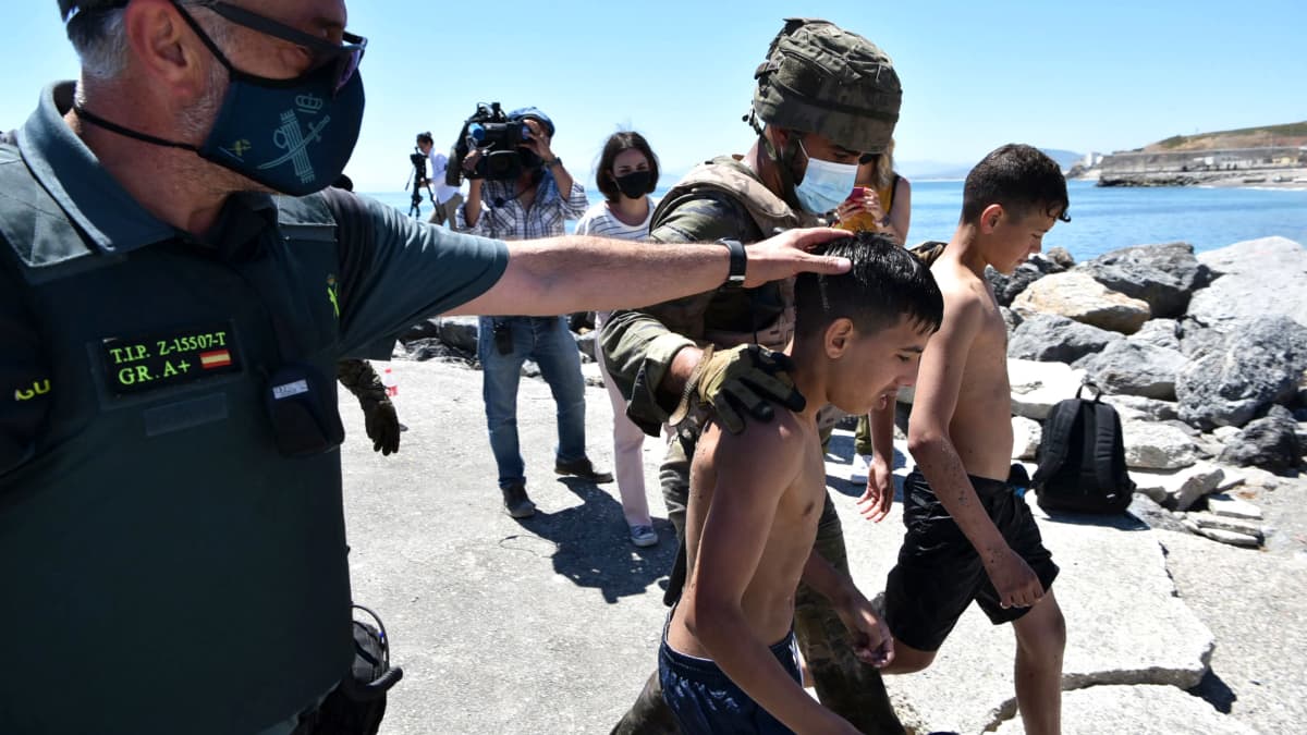Sotilaat taluttavat maahan pyrkivää lasta Espanjan rannikolla.