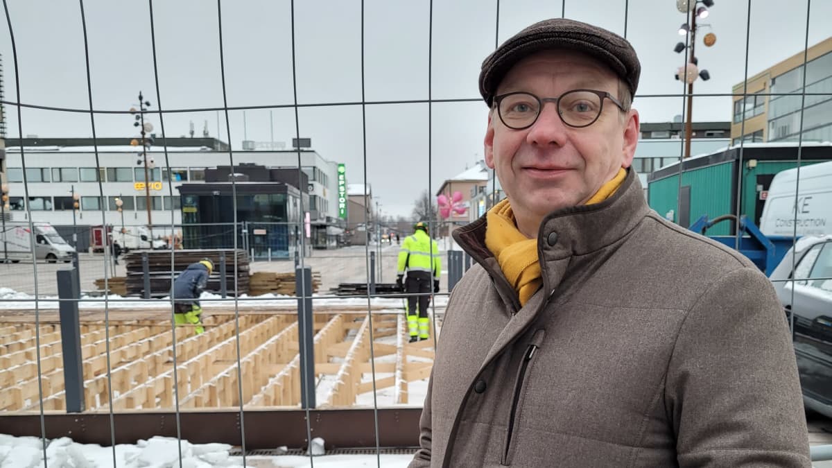 Jussi Aittoniemi seisoo työmaa-aidan edessä Seinäjoen keskustassa ja katsoo kameraan.