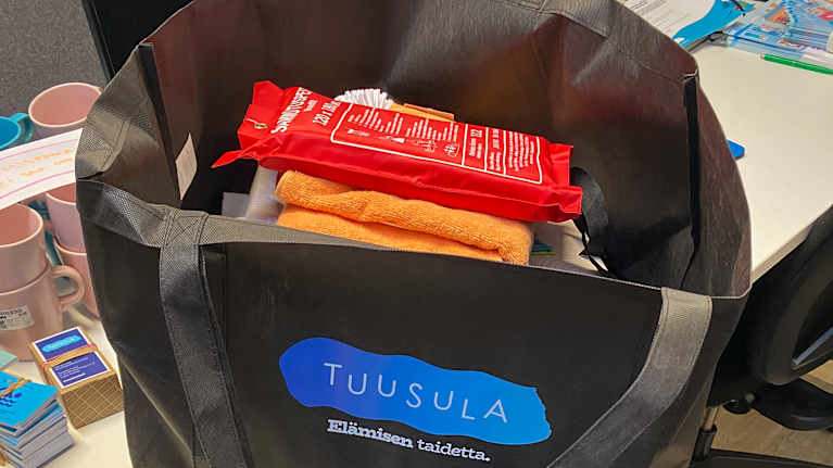 Kodintavaroita kuten kattila, sammutuspeite, vessaharja ja pyyhe isossa kestokassissa.