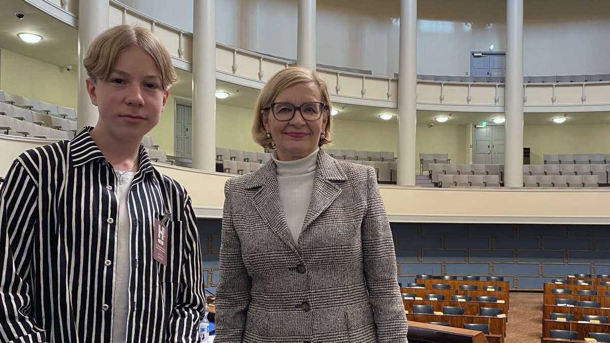 TET-harjoittelija Elias Hiltunen Kouvolasta varapuhemies Paula Risikon (kok.) kanssa eduskunnan istuntosalissa puhemiehen korokkeella.