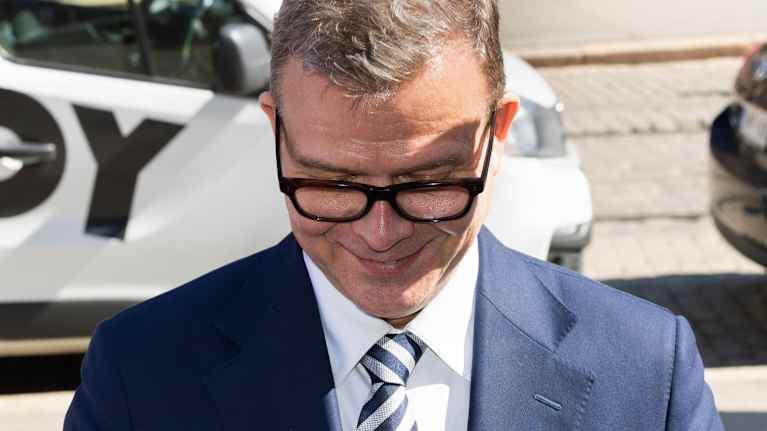 A smiling middle-aged man in glasses looks down.