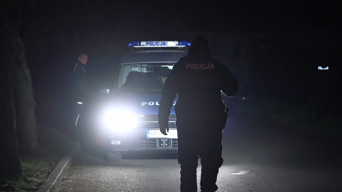 Puolalaisia poliiseja ja poliisiauto pimellä tiellä.