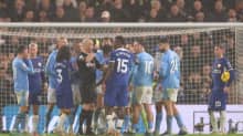 Manchester Cityn ja Chelsean pelaajat piirittävät tuomari Anthony Tayloria.