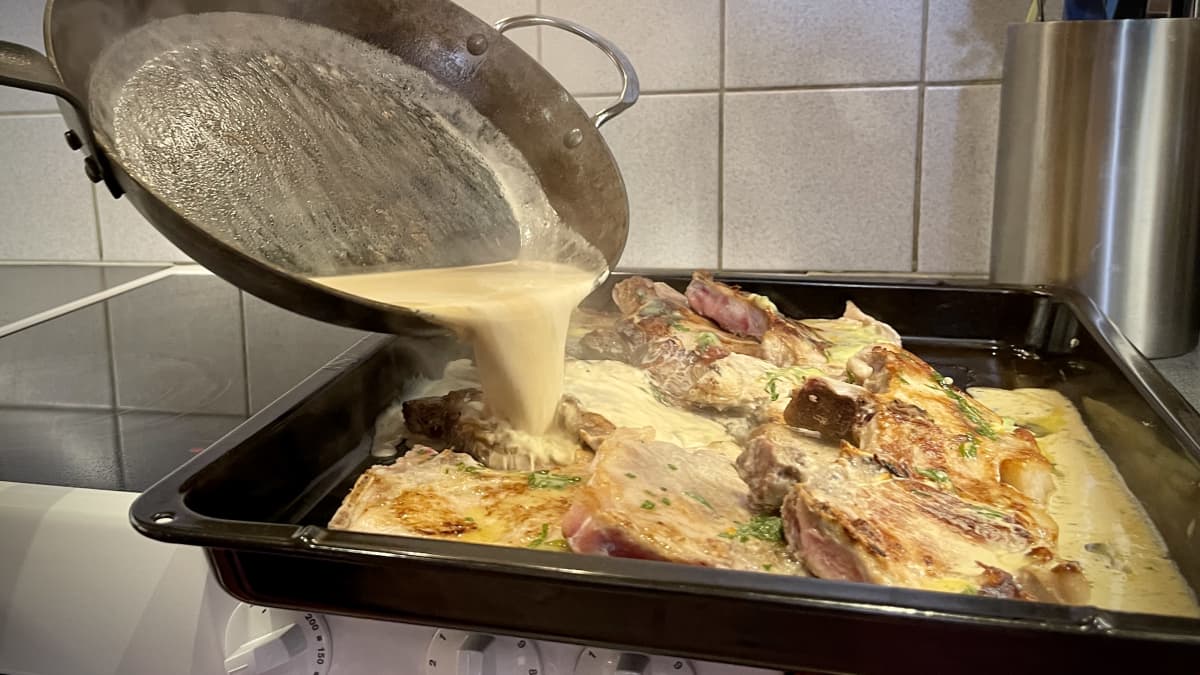 Sås hälls över kotletter på en ugnsplåt.