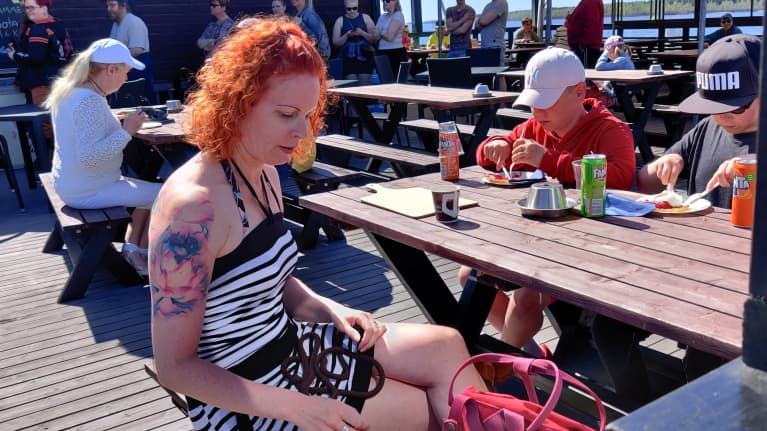 Ihmisiä kesäterassilla juomassa kavhia ja syömässä pannaria, takana jonotetaan tiskille.