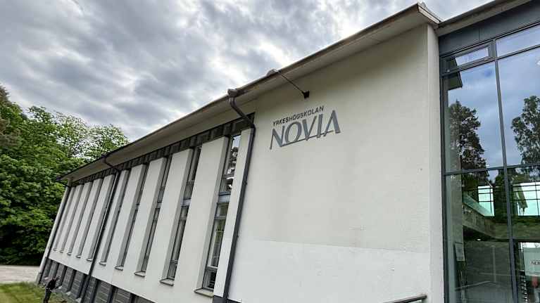En modern byggnad med stora glaspartier och texten "Novia" på fasaden.
