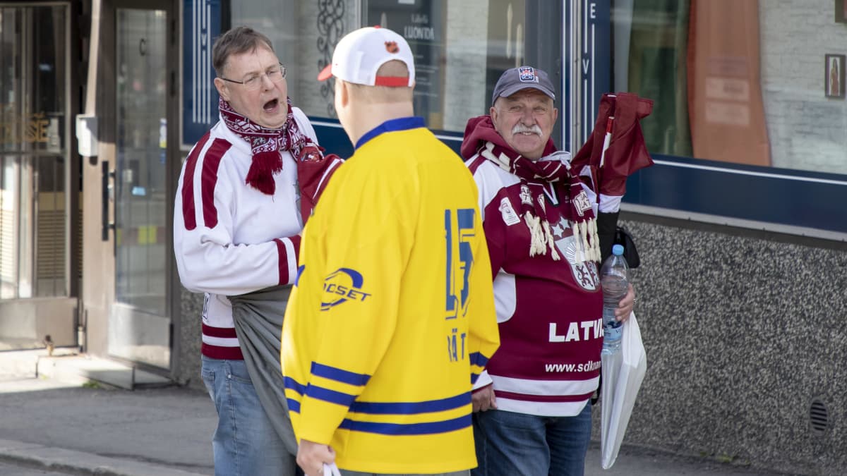 Ruotsalaiskannattaja keskustelemassa kahden latvialaisen kanssa.