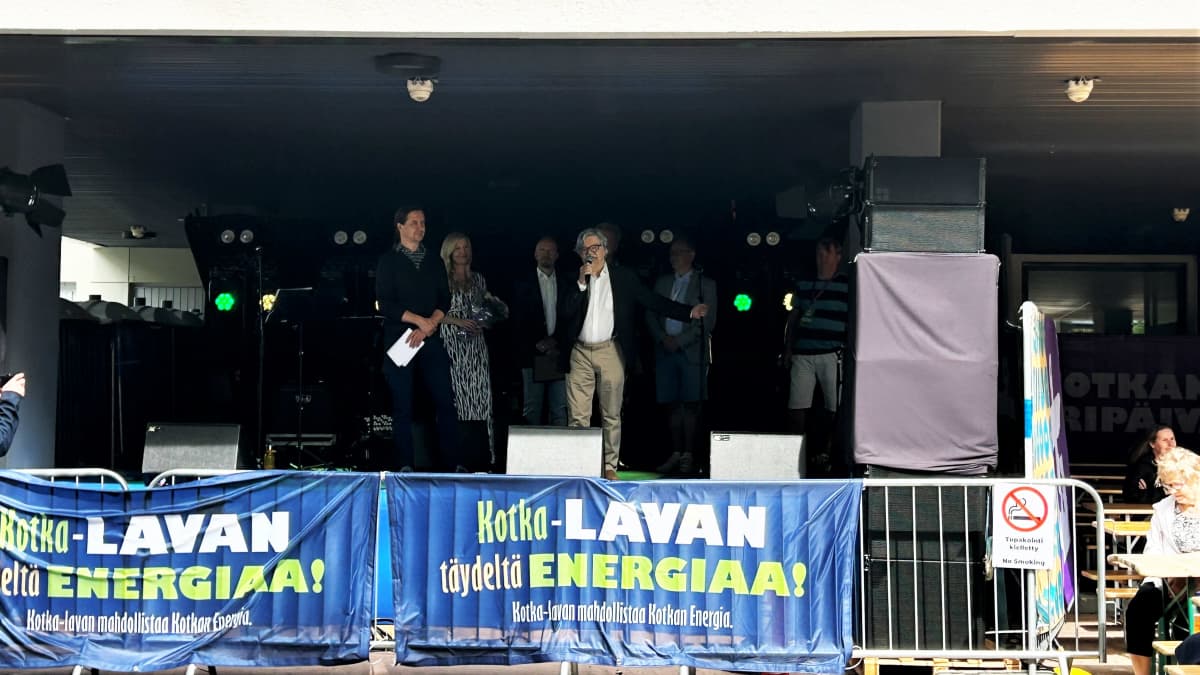 Lavalla kuusi ihmistä. M.A.Numminen puhuu mikrofoniin. 