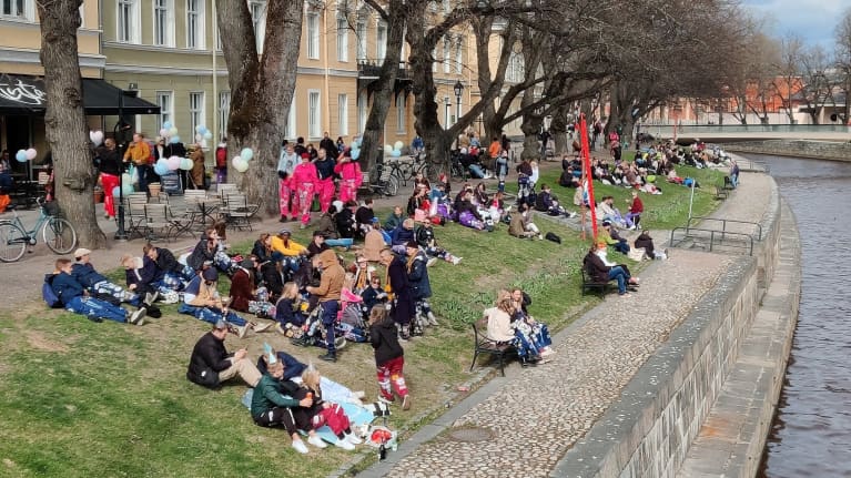 People sitting on the banks of the Aura River in Turku. The grass is already turning green.