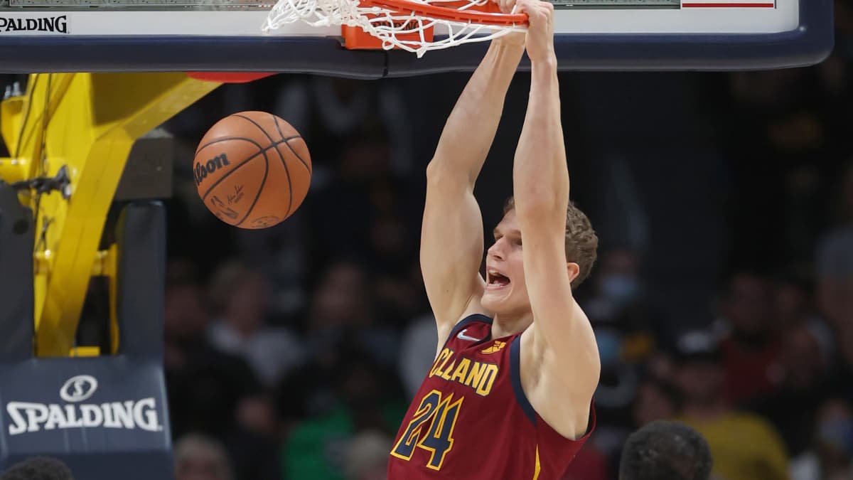 Lauri Markkanen i vinröd spelblus hänger kvar i korgen efter en dunk.