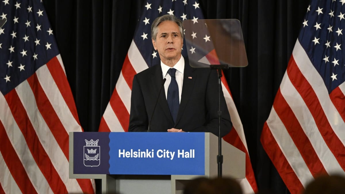 Antony Blinken står vid ett talarpodium och pratar. I bakgrunden flera USA-flaggor.