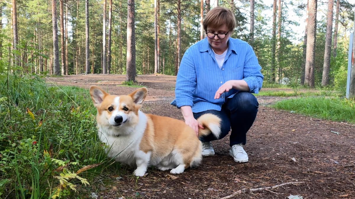 Olga Filippova on kyykistynyt rapsuttamaan corgirotuista Winston-koiraansa.