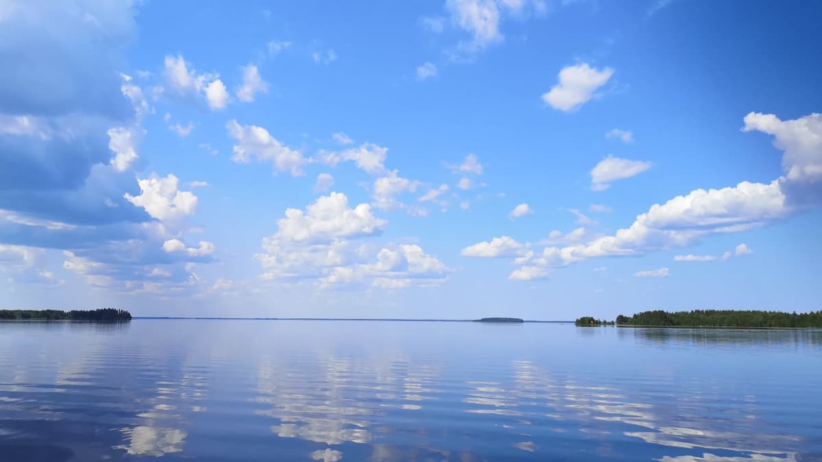 Aurinkoinen päivä järvellä. Hattarapilviä taivaalla. 