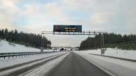An electronic sign above a snowy highway.