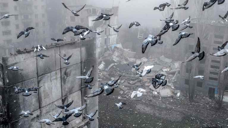 Iso parvi puluja lentää pommitettujen kerrostalojen välissä sumuisessa säässä Donetskin alueella Ukrainassa.