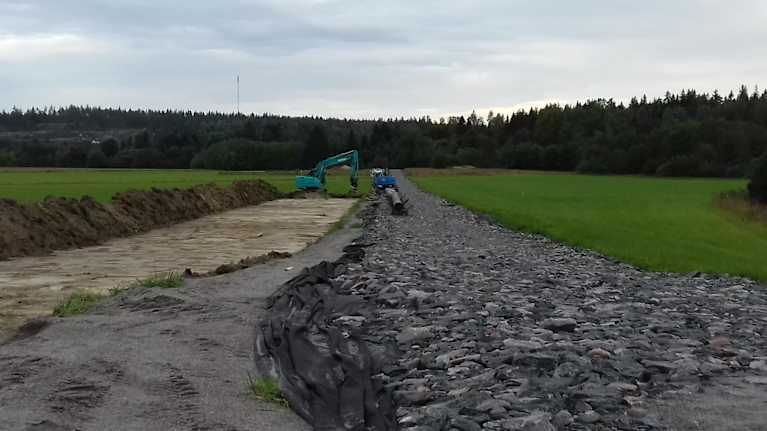 Ett gasrör grävs ner rakt över en åker.