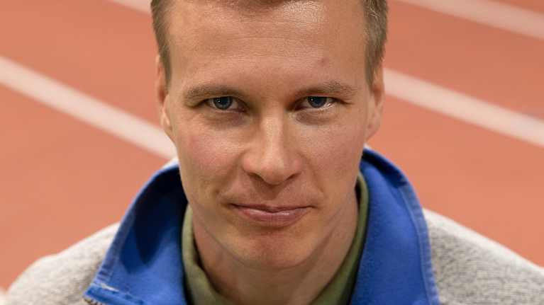 Matti Heikkinen katsoo suoraan kameraan. Hänen takanaan näkyvat punaiset juoksuradan valkoset ratamerkinnät.