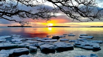 Aamu Helsingissä meren äärellä. Tuuli on hajoittanut jäälautat. Aurinko horisontissa. 