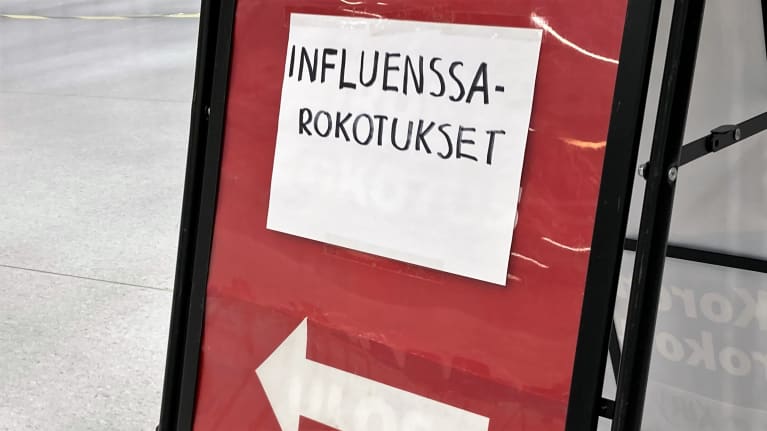 Kyltti, jossa teksti INFLUENSSAROKOTUKSET ja nuoli, joka osoittaa rokotuspaikalle.