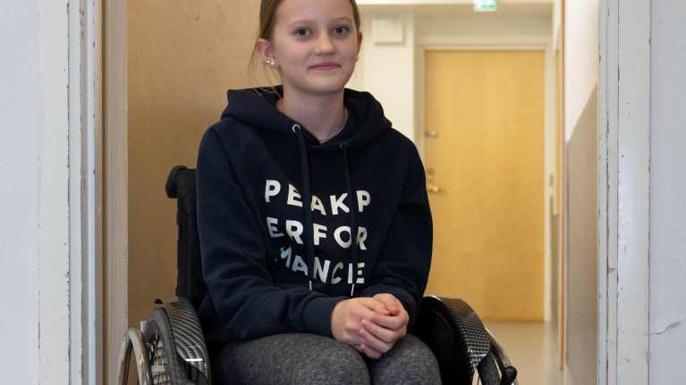 Keminmaalainen Elli Huusko kokeilemassa pyörätuolia koulun liikuntasalissa.