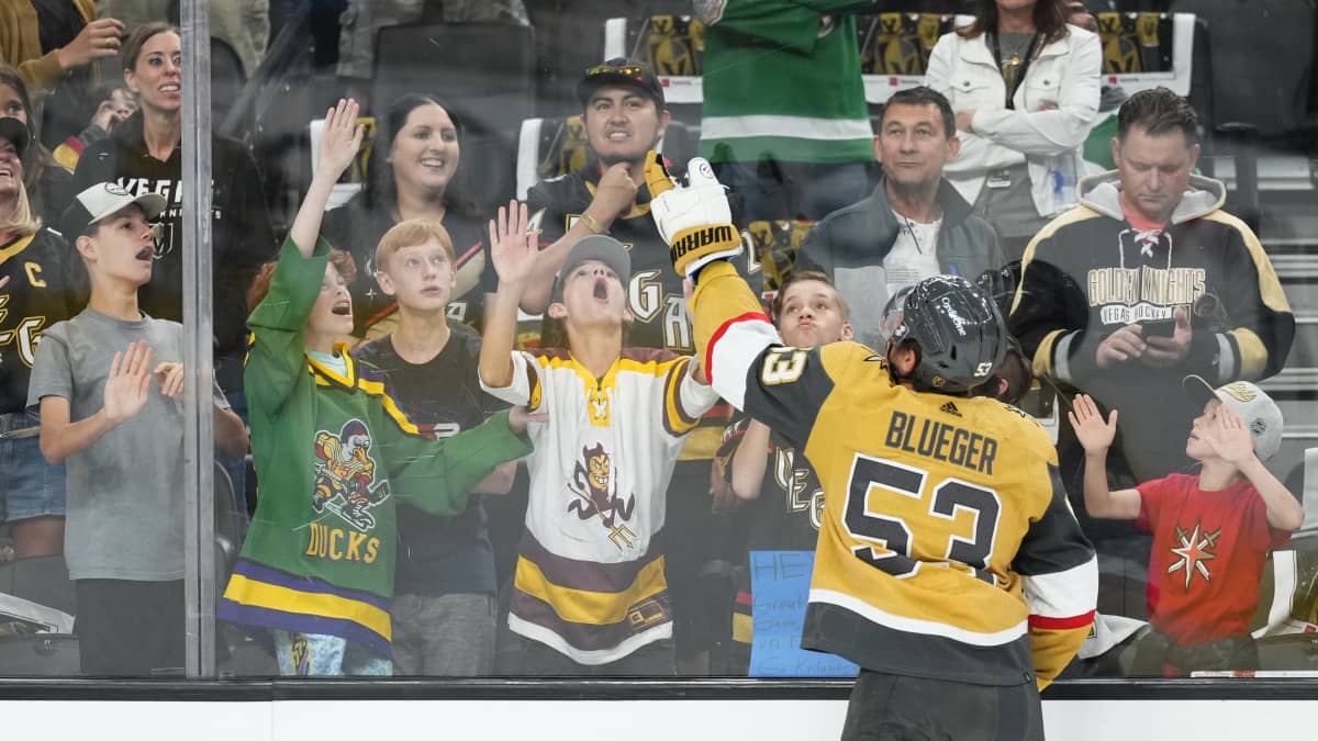 Vegas Golden Knightsin pelaaja Teddy Blueger heittää kiekon nuorille faneille kaukalon laidan yli.