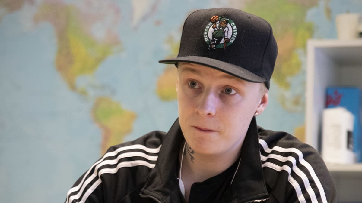 Patrik Lindblom istuu pöydän äärellä lippis päässään.