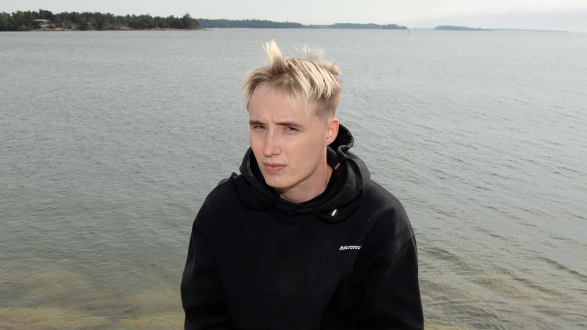 Isac Elliot istuu rantakiveyksellä.
