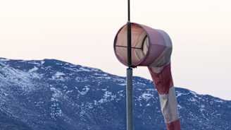 Tuulipussi lentokentällä. Taustalla lennojohtotorni ja lumeton vuori.