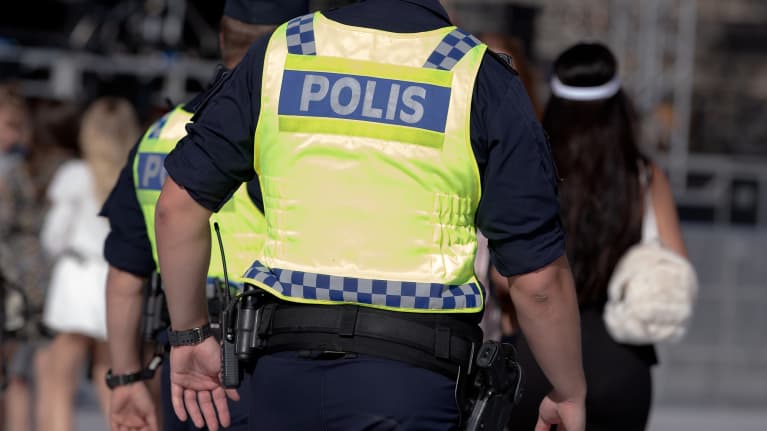 Kaksi poliisia huomioliivit päällään. Kuvassa mukana myös jalankulkijoita.