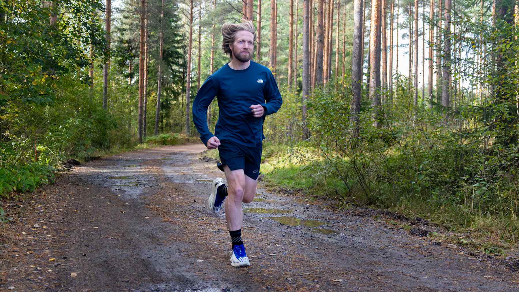 Mies juoksee metsätiellä.