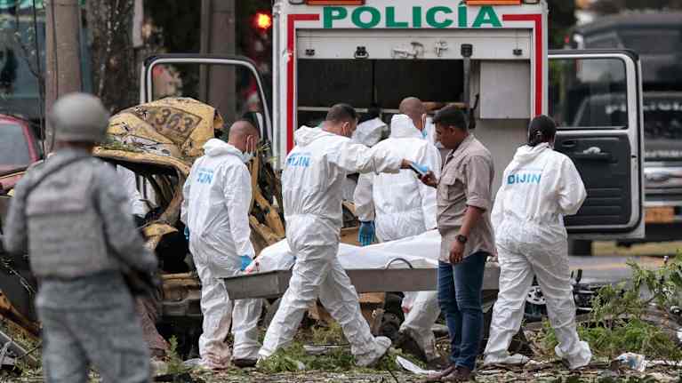 Suojavarusteisiin pukeutuneet poliisit kantavat paareilla lakanalla peitettyä iskun uhria.