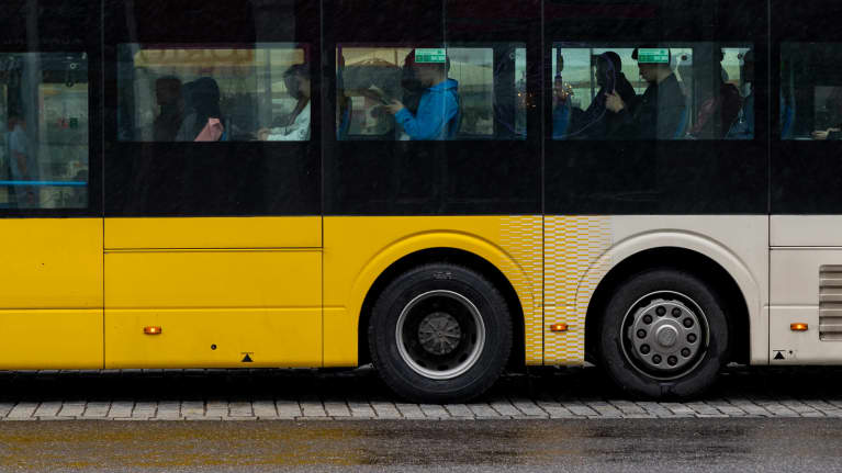 Ihmisiä istumassa bussin sisällä sadesäällä.