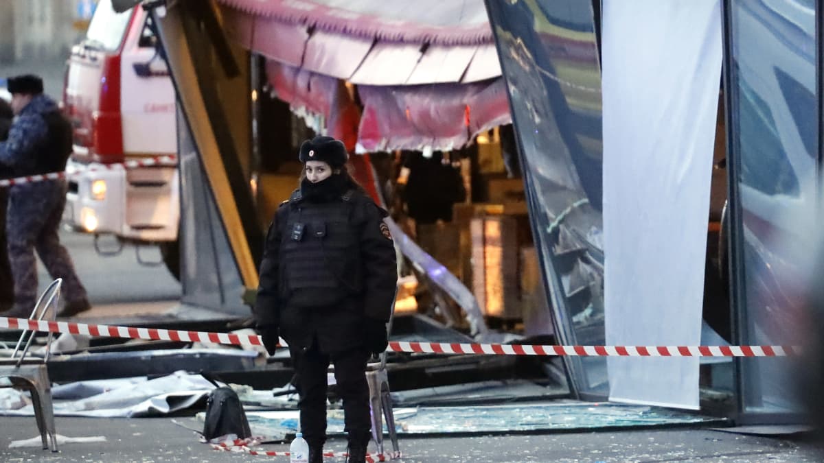 Naispoliisi vartioi räjähdyspaikkaa Pietarissa Street Bar -kahvilan edessä.