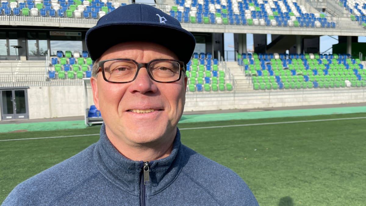 Rovaniemen kaupungin liikuntajohtaja Pekka Hämäläinen seisoo Keskuskentän jalkapallokentällä ja hymyilee kameralle.