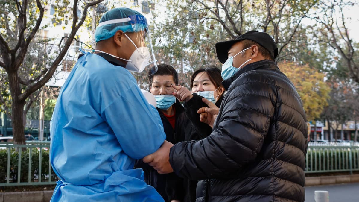 Ihmiset väittelevät terveydenhuoltohenkilön kanssa koronatestipaikalla Kiinassa.
