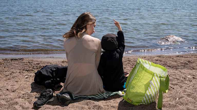 Kesäpäivää viettäviä ihmisiä uimarannalla.