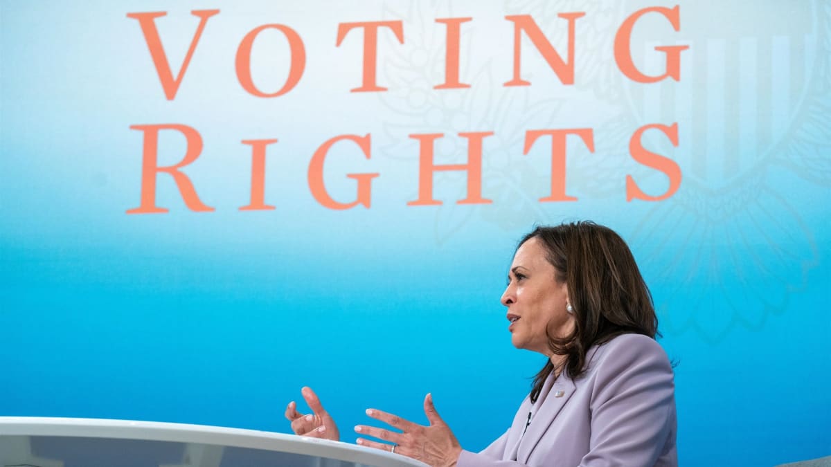 Kamala Harris puhuu pöydän ääressä. Taustakankaassa lukee "Voting rights".
