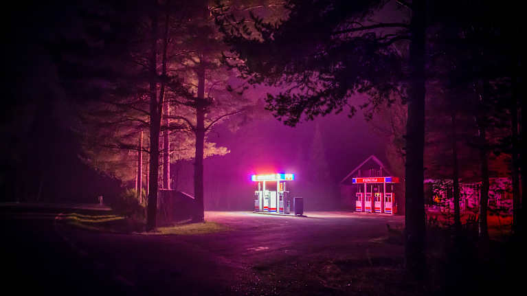 Autio bensa-asema pinkin sävyisessä valossa.