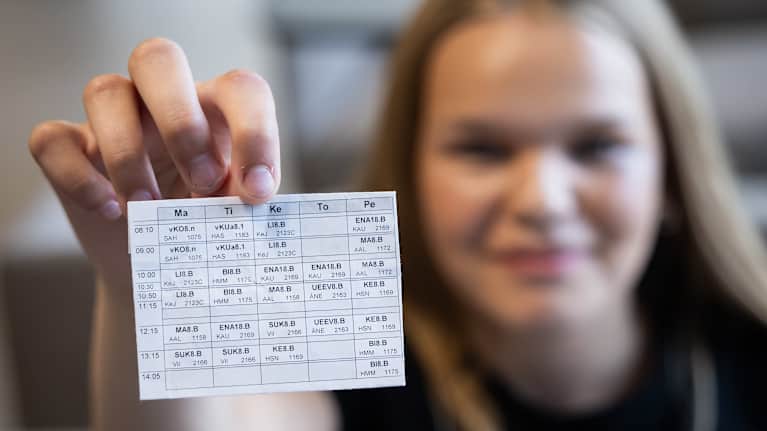 The girl holds a tag in her hand with boxes with text.