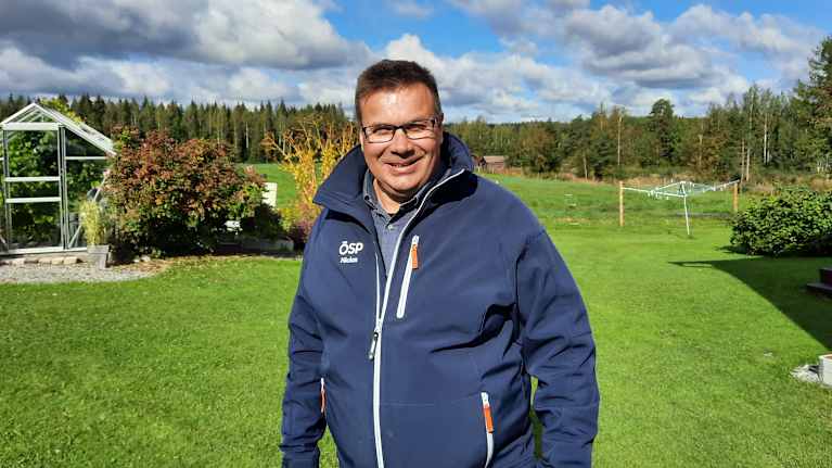 Man som står utomhus på en gräsmatta på landet. 