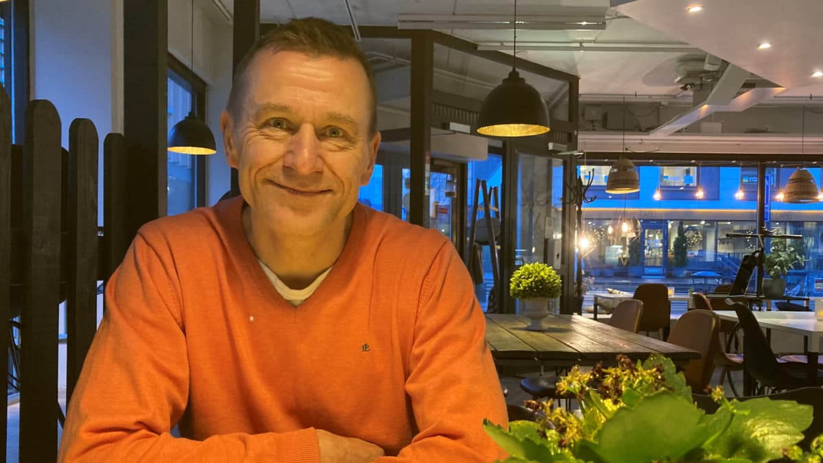 Kahvikupillisen ääressä istuva Juha Lantz katsoo hymyillen kameraan.