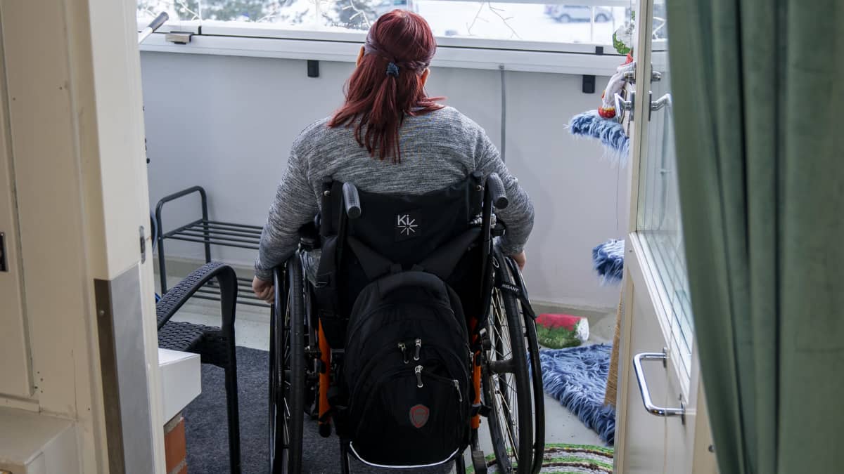 Kehitysvammainen Eveliina pyörätuolissa asuntonsa parevekkeella.