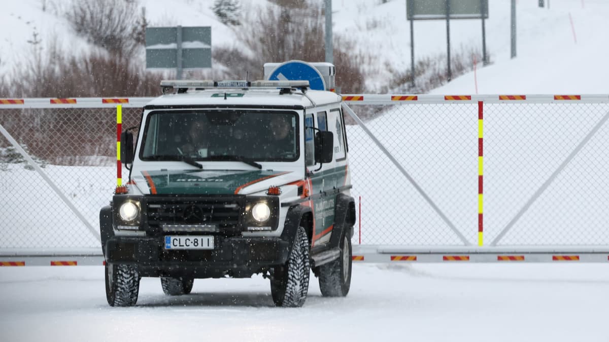 Rajavartiolaitoksen maastohenkilöauto seisoo rajapuomien edessä lumisena päivänä Vartiuksen suljetulla rajanylityspaikalla.
