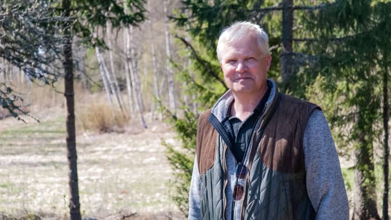 En man står i ett skogsbryn