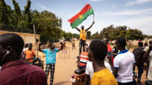 Ihminen heiluttaa Burkina Fason lippua väkijoukossa kadulla.