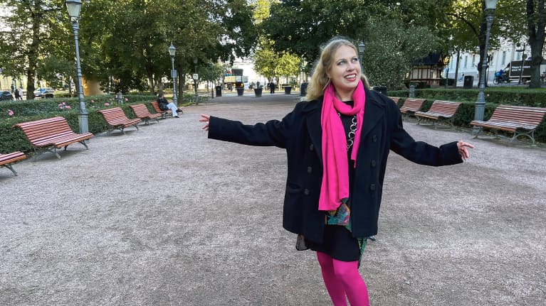 Soile Vilponen seisoo Esplanadinpuiston hiekkakäytävällä ja katsoo taivaalle.