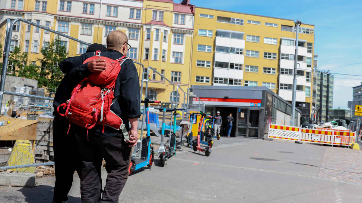 Ihminen kävelee toisen tukemana Vaasanpuistikon laitaa.
