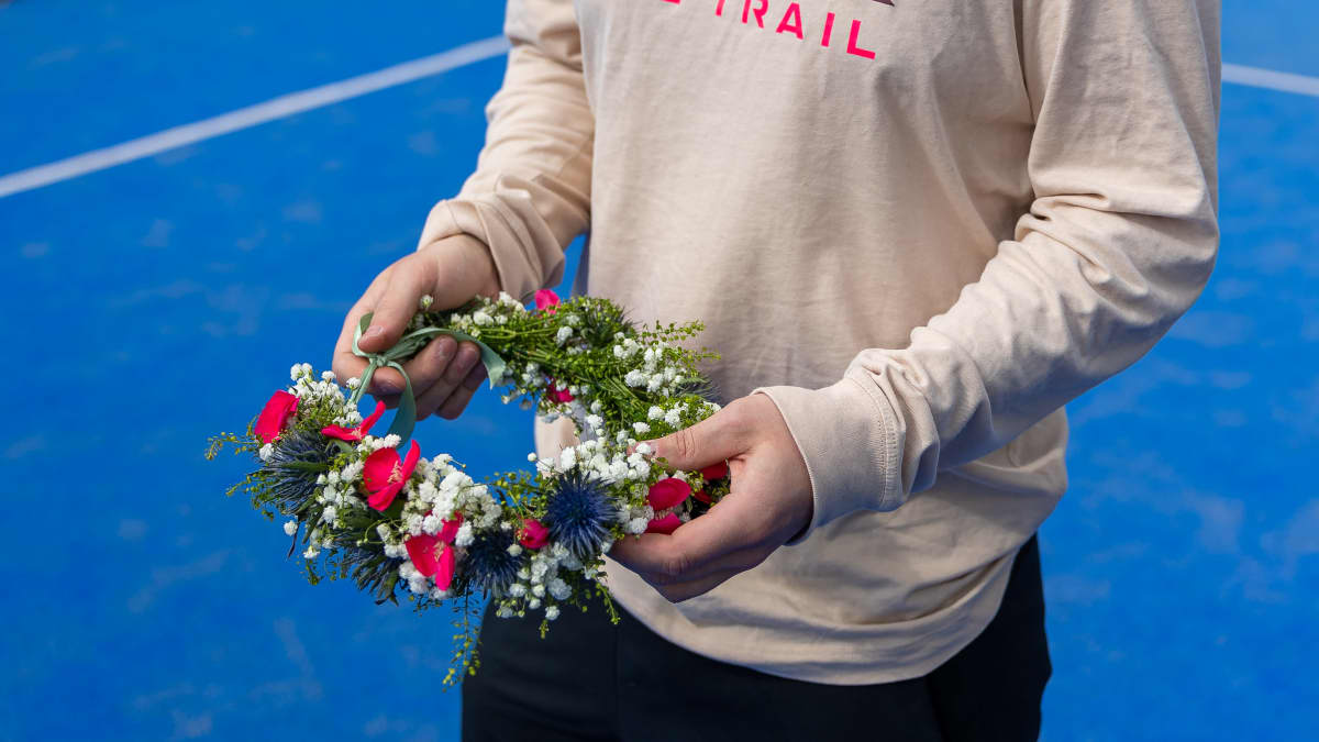 Kukkaseppele miehen kädessä tenniskentällä