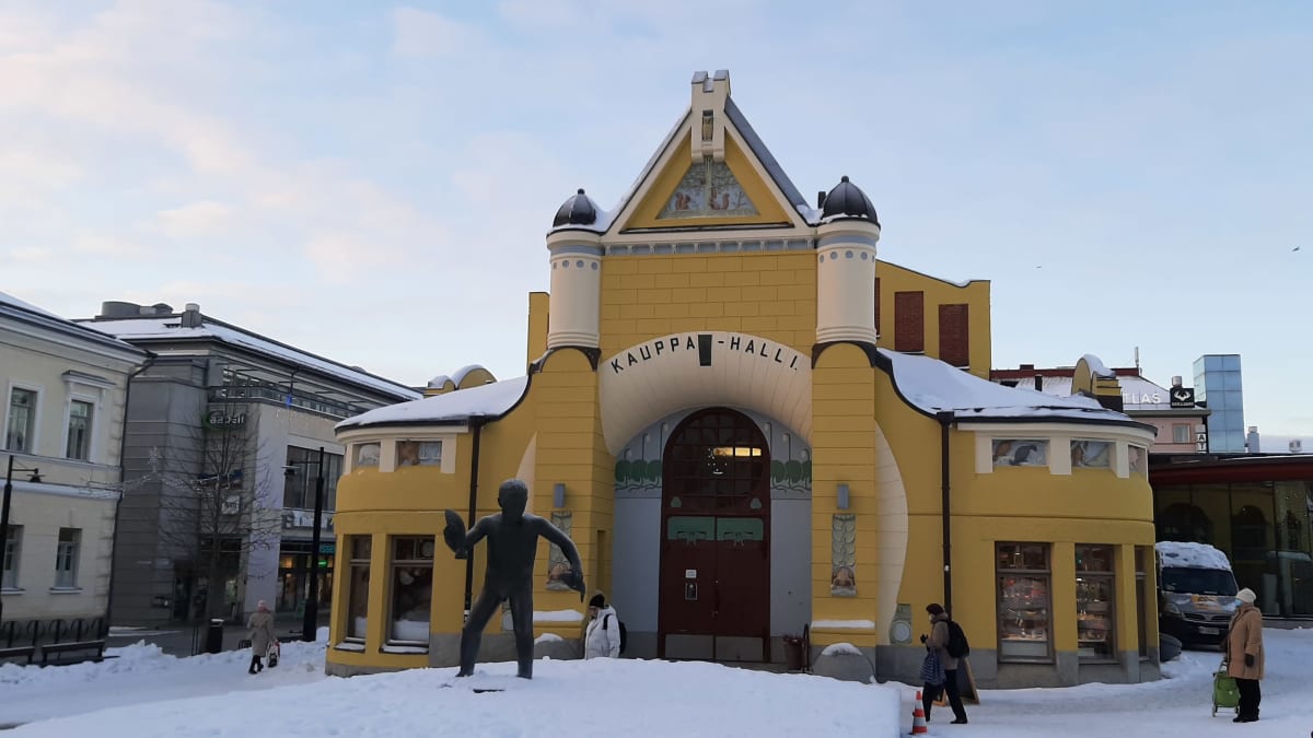 Kuopion kauppahalli talvisessa maisemassa. Etualalla Veljmies-patsas.